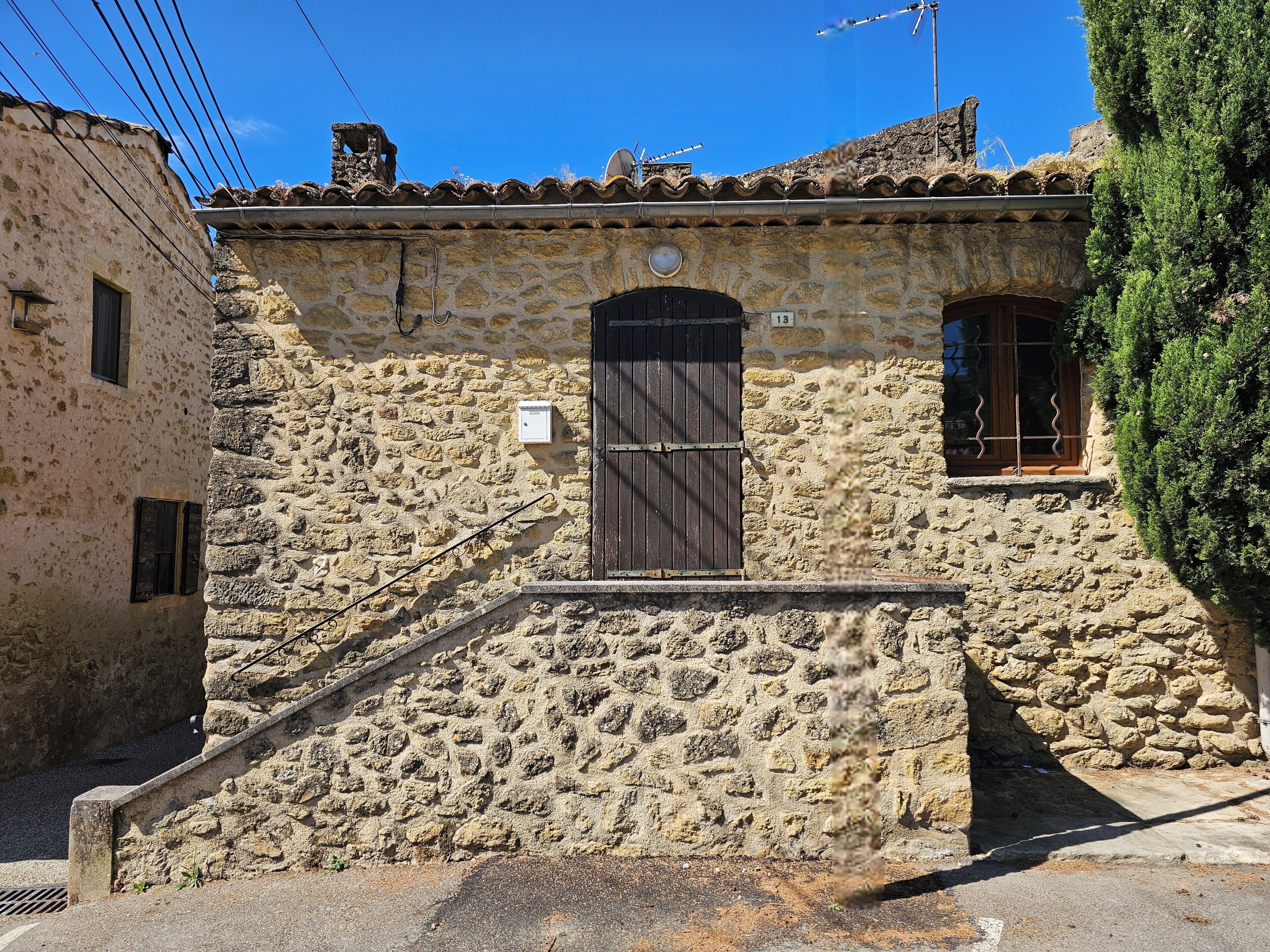 Un edificio de piedra con puerta de madera, una ventana pequeña y una antena parabólica.