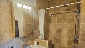 A bathroom with a sink, mirror, shower, and tiled walls. - Small apartment in the village (Lauris)