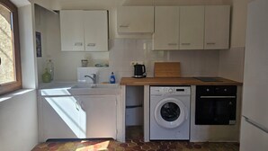 A compact kitchen with a washing machine, dishwasher, and a wooden countertop. - Small apartment in the village (Lauris)