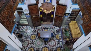 A room with a patterned floor, a central table with chairs, and ornate wooden cabinets.