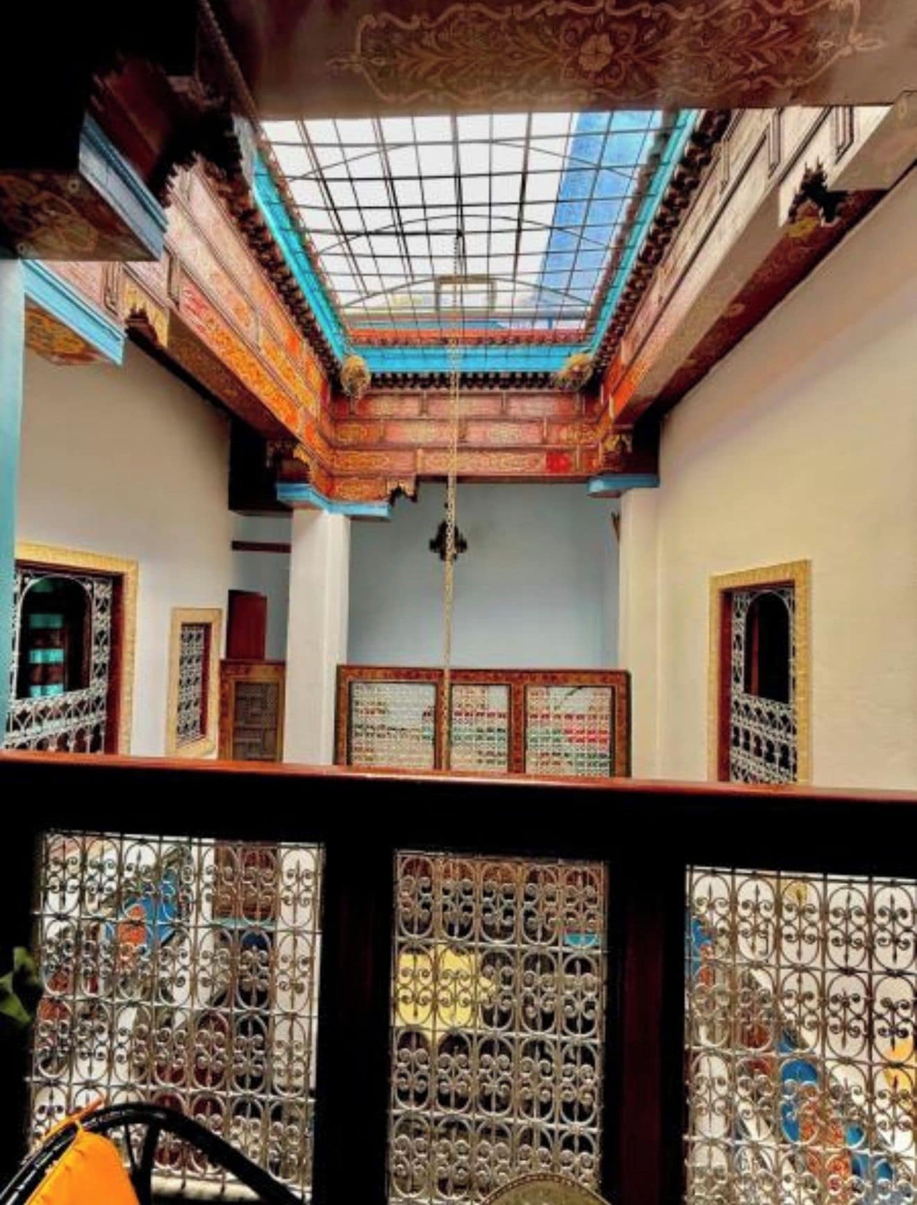 An interior with a traditional ceiling design, a central hanging object, and ornate wooden doors.