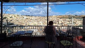 A balcony with a view of a cityscape, a table, and chairs.