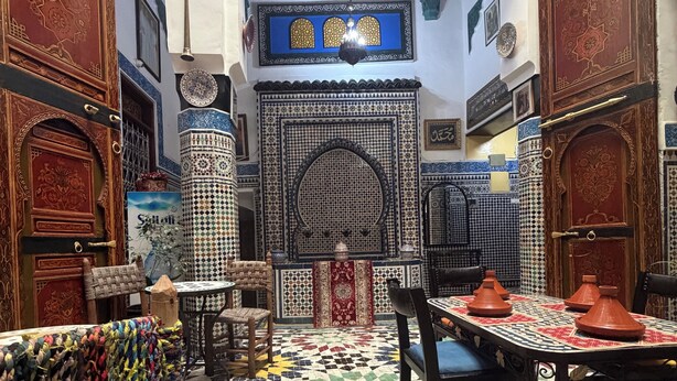 A traditional interior with patterned tile flooring, wooden furniture, and ornate doors.