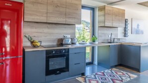 A modern kitchen with wooden cabinets, a red refrigerator, and a view of greenery outside. - Large Holiday Villa With Sauna and Mountain Views (Bukowina Tatrzanska)