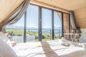 Een slaapkamer met een groot raam, een bed, een tafel en een stoel.