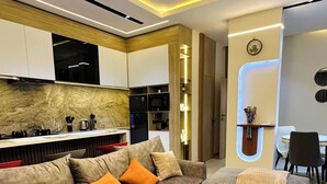 Ein modernes Wohnzimmer mit Ecksofa, Couchtisch und integrierten Küchengeräten.