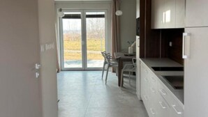 Eine moderne Küche mit Essbereich, großen Fenstern und Blick ins Freie.