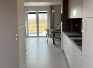 A modern kitchen with a dining area, large windows, and a view of the outdoors. - Half of a Holiday Home With a Large Garden (Choczewo)