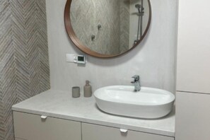 Un baño con un espejo redondo, un lavamanos blanco y una pared con motivo de espiga.
