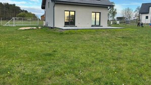 Ein modernes, zweistöckiges Haus mit geneigtem Dach, großen Fenstern und einem Rasen.