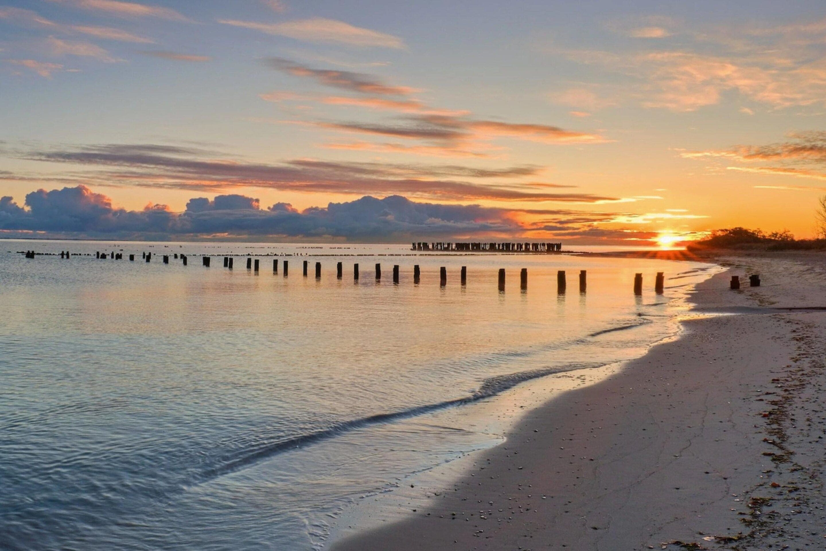 Een strand met een houten steiger die zich uitstrekt in rustig water.