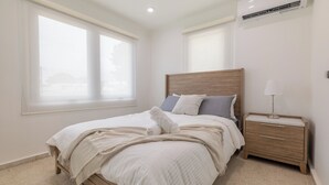 Ein Schlafzimmer mit einem hölzernen Bett, einem Nachttisch, einer Lampe und einem Fenster mit Jalousien.