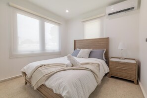 Ein Schlafzimmer mit einem hölzernen Bett, einem Nachttisch, einer Lampe und einem Fenster mit Jalousien.