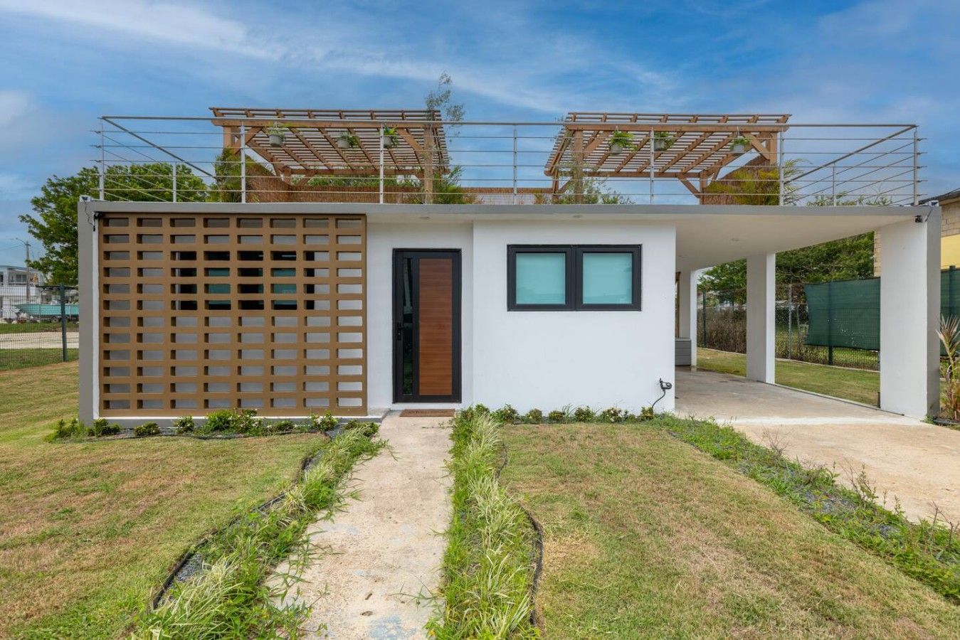 A modern building with a wooden lattice facade, a small entrance, and a covered outdoor area.