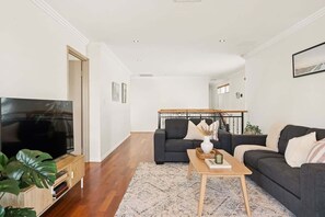 Ein Wohnzimmer mit Fernseher, zwei Sofas, einem Couchtisch und einer Treppe im Hintergrund.