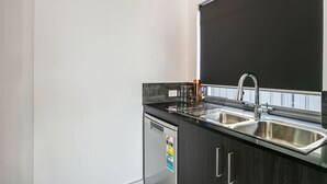 Eine moderne Küche mit schwarzem Arbeitsplatz, Spüle aus Edelstahl und Geschirrspüler.