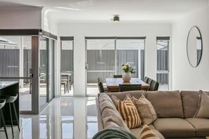 A modern interior with a sofa, dining table, and chairs. - Kids Play Room | 75 Inch TV | WFH Space (Wembley Downs)
