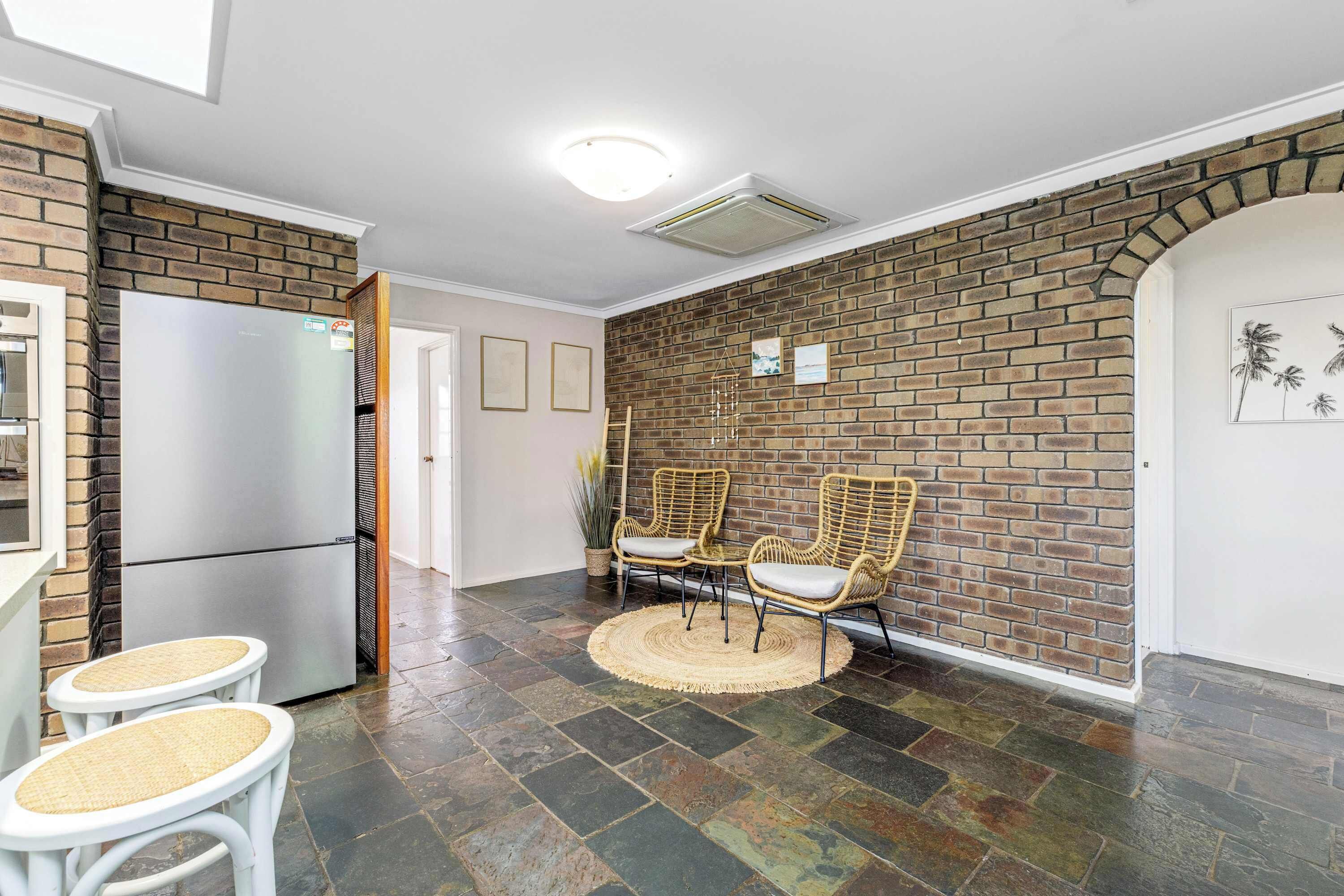 A kitchen with a refrigerator, a sink, and a dining area with chairs and a table.