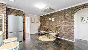 A kitchen with a refrigerator, a sink, and a dining area with chairs and a table.