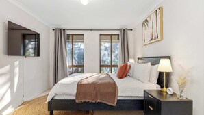Un dormitorio con cama, mesita de noche, lámpara y una obra de arte.
