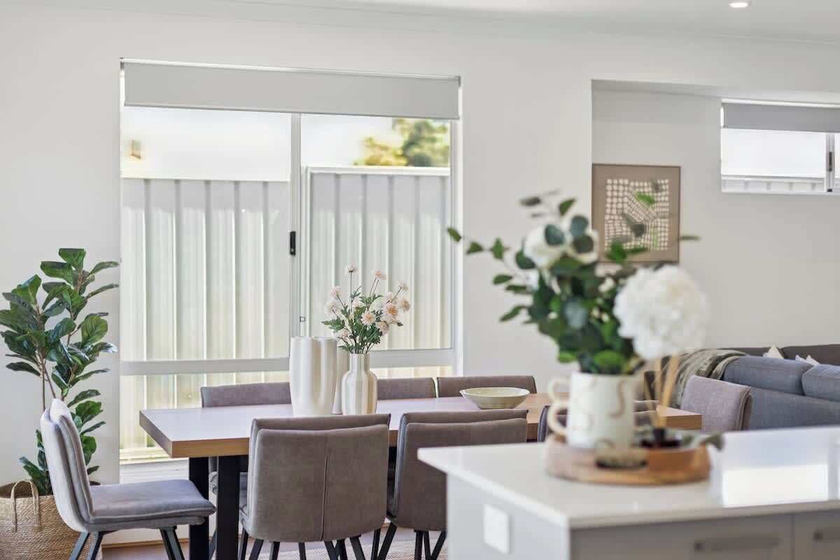 A modern dining area with a table, chairs, and a vase of flowers.