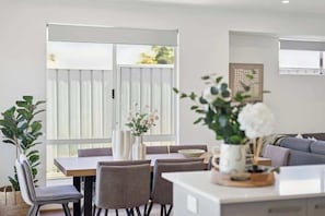 A modern dining area with a table, chairs, and a vase of flowers.