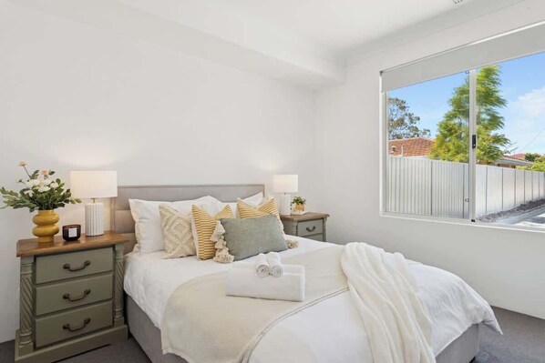 A bedroom with a bed, bedside tables, lamps, and a window with a view.
