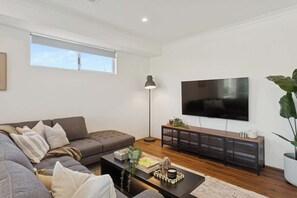 A modern living room with a sofa, coffee table, TV, and a plant.