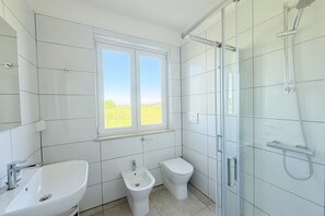 Un bagno con lavandino, bidet, toilette e cabina doccia in vetro.