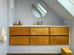 Ein Badezimmer mit einem Holzkosmetikschrank, einem runden Spiegel und einem Handtuch an der Wand.