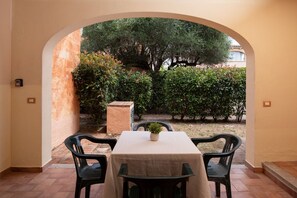 A table with a beige tablecloth, two black chairs, and a potted plant in the center. - Casa del Leccio F4 by Wonderful Italy (San Teodoro)