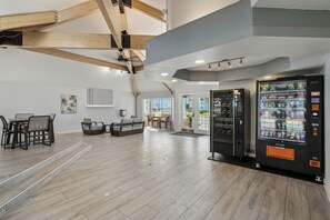 A spacious room with a dining area, a sofa, and vending machines. - The Magic Hideaway / Disney Escape w/ Pool, Hot Tub & Gym (Kissimmee)