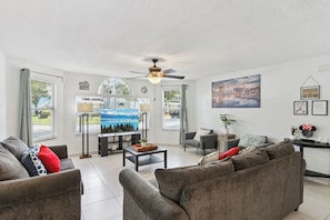 A living room with a sofa, armchairs, a coffee table, a TV, and a ceiling fan. - The Magic Hideaway / Disney Escape w/ Pool, Hot Tub & Gym (Kissimmee)