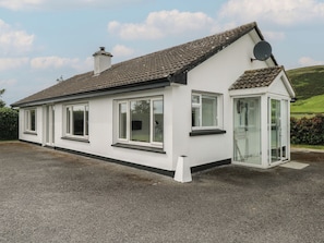 A single-story house with a tiled roof, white exterior walls, and a satellite dish. - Tí Chonaill (Louisburgh)