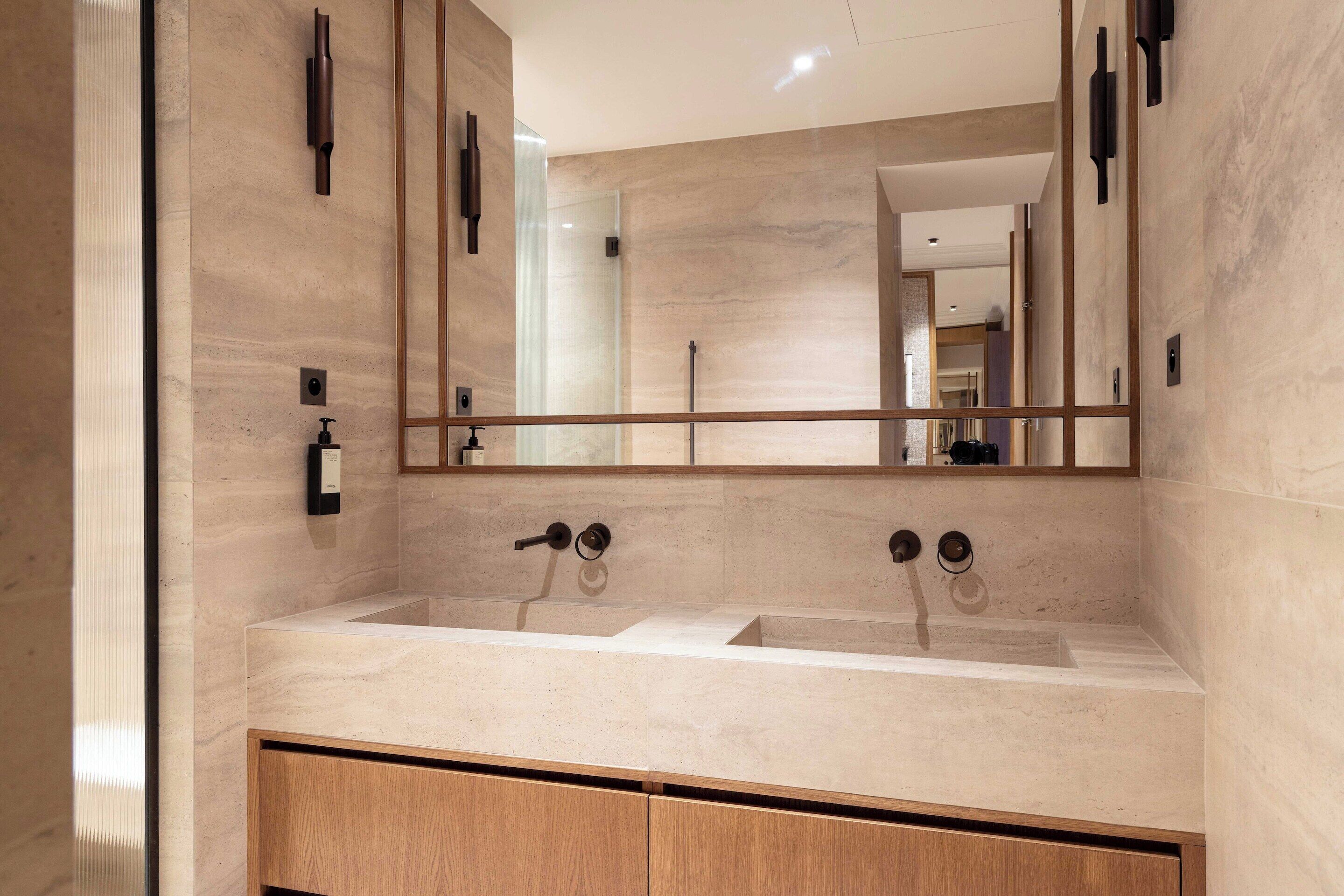 A modern bathroom with a large mirror, two sinks, and wooden cabinets.