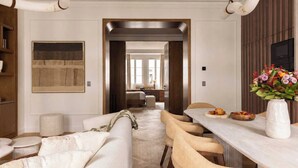 Ein modernes Interieur mit Essbereich, einer Couch, einem Tisch mit einer Vase und einem Gang zu einem weiteren Zimmer.