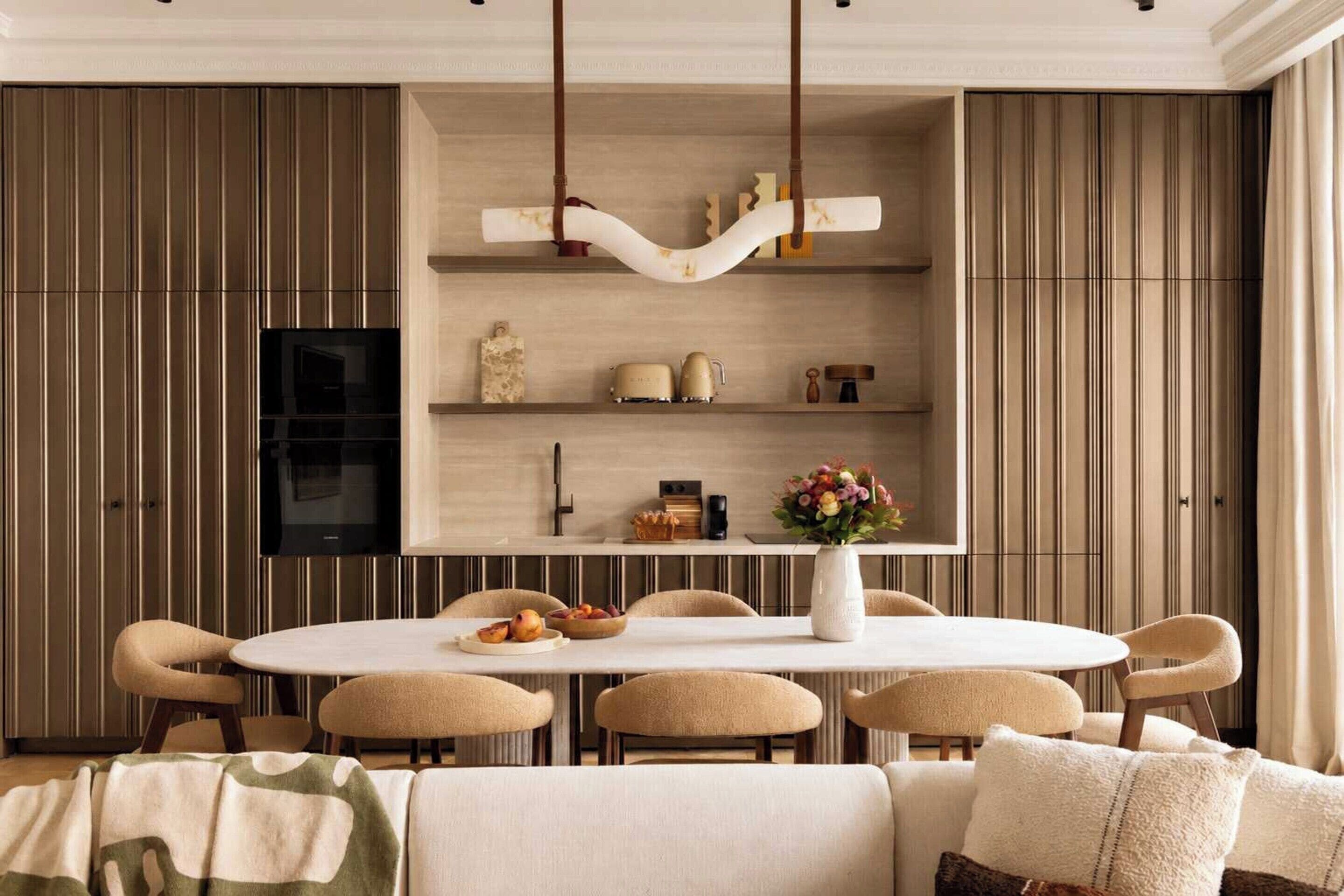 A modern dining area with a round table, chairs, and a television above.