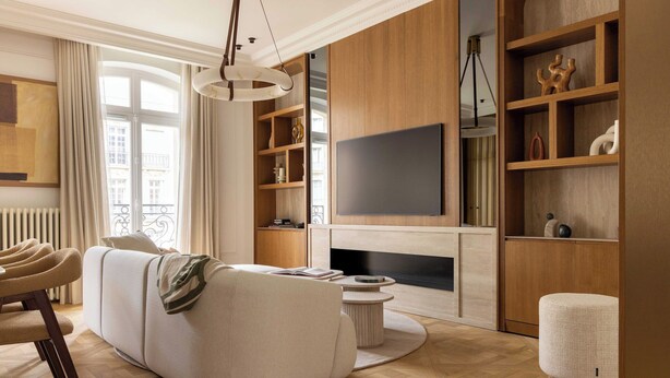 Ein modernes Wohnzimmer mit einer Couch, einem Couchtisch, einem Fernseher, Holzregalen und einem Kamin.