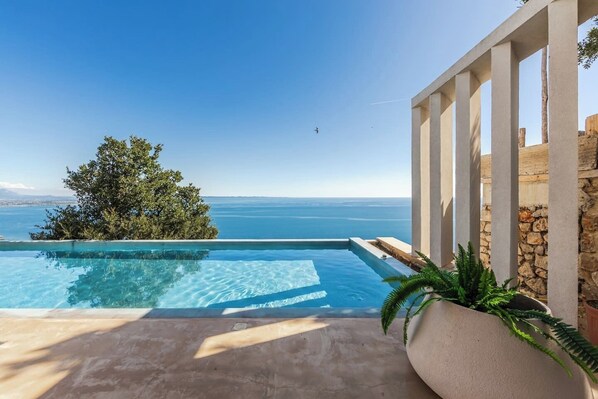 A clear view of a swimming pool with a view of the sea and a tree.
