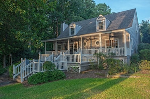 A two-story house with a porch, a staircase, and a small garden area. - Waterfront Home Near Real Island (Eclectic)