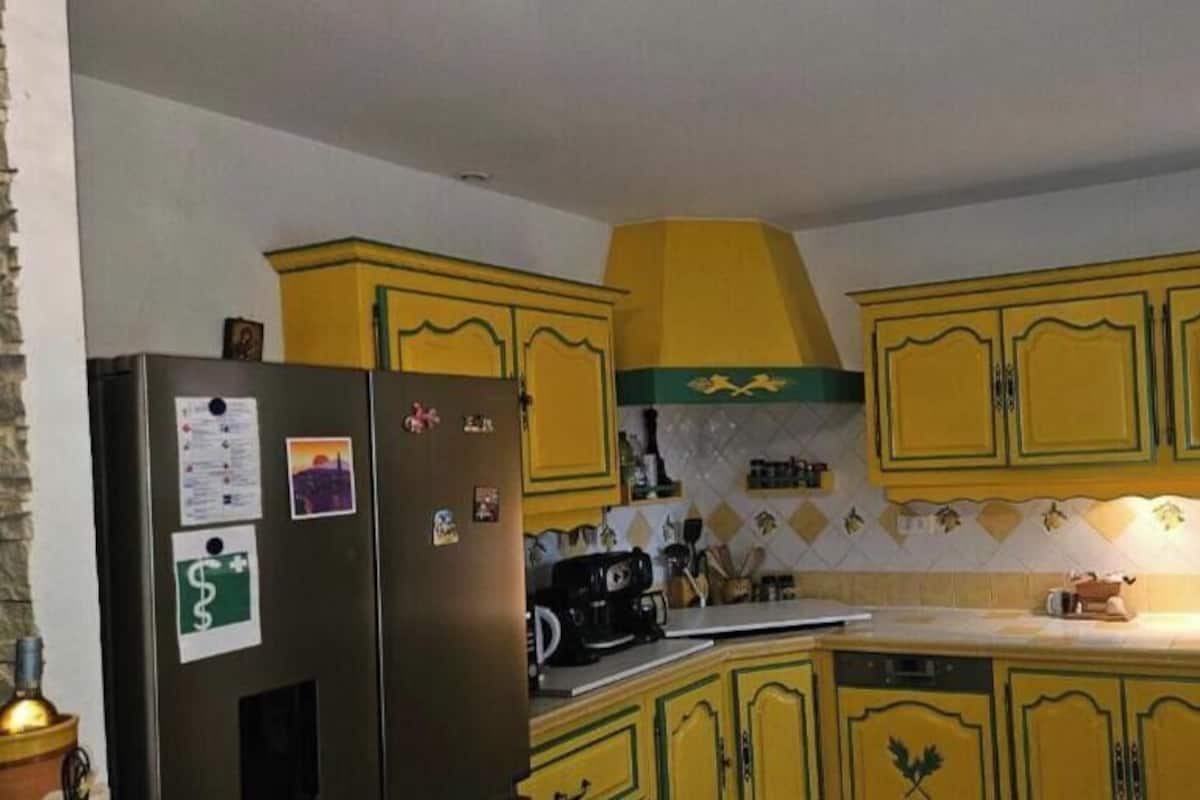 Una cocina con armarios amarillos, un refrigerador y un salpicadero de azulejos.