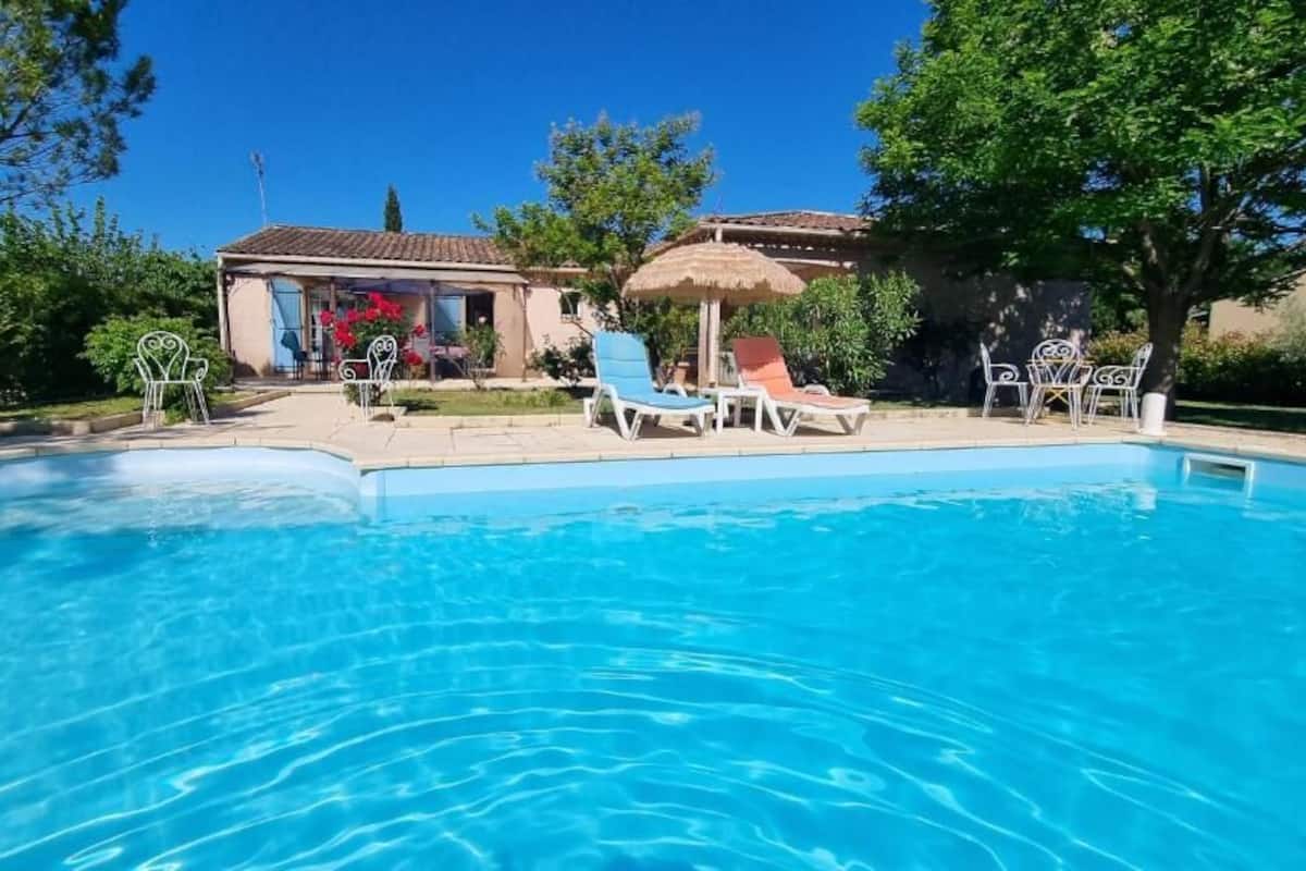 Una piscina con sillas de descanso y un edificio al fondo.