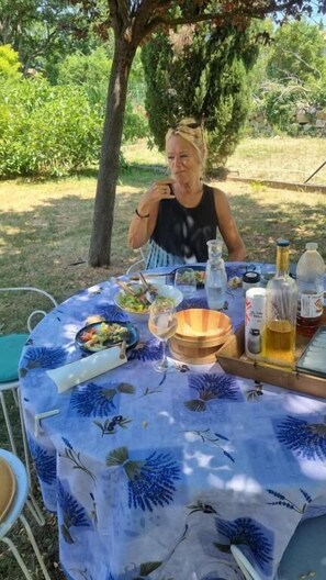 Een tafel buiten gedekt, met een tafelkleed, eten en drinken.
