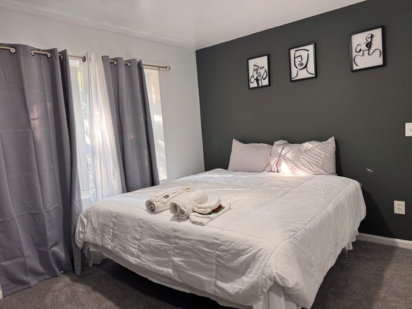 A neatly made bed with white linens and towels, a grey curtain, and three framed artworks on the wall. - Large 2 Kings bedroom , 2 bathrooms byEWR/NYC Downtown Newark (Newark)