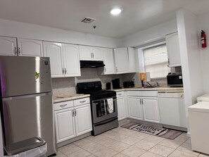 A modern kitchen with white cabinets, stainless steel appliances, and a tiled floor. - Large 2 Kings bedroom , 2 bathrooms byEWR/NYC Downtown Newark (Newark)
