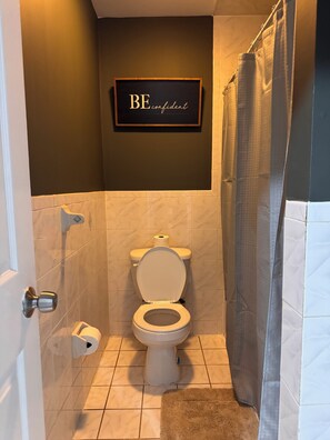 A bathroom with a toilet, a shower curtain, and a motivational sign on the wall. - Large 2 Kings bedroom , 2 bathrooms byEWR/NYC Downtown Newark (Newark)