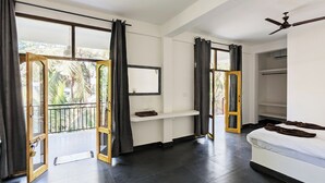Een slaapkamer met een bed, een kledingkast, een spiegel en een balkondeur.