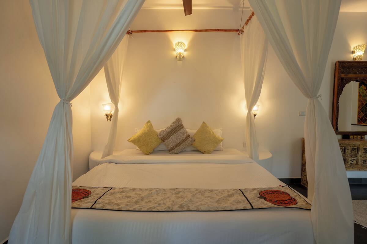 A bed with a canopy, pillows, and wall-mounted lights.