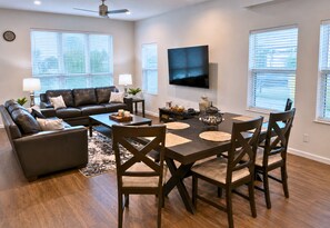 A modern living room with a sofa, coffee table, and dining table with chairs. - Skyline Views | Rooftop Deck | Minutes to Downtown (San Antonio)