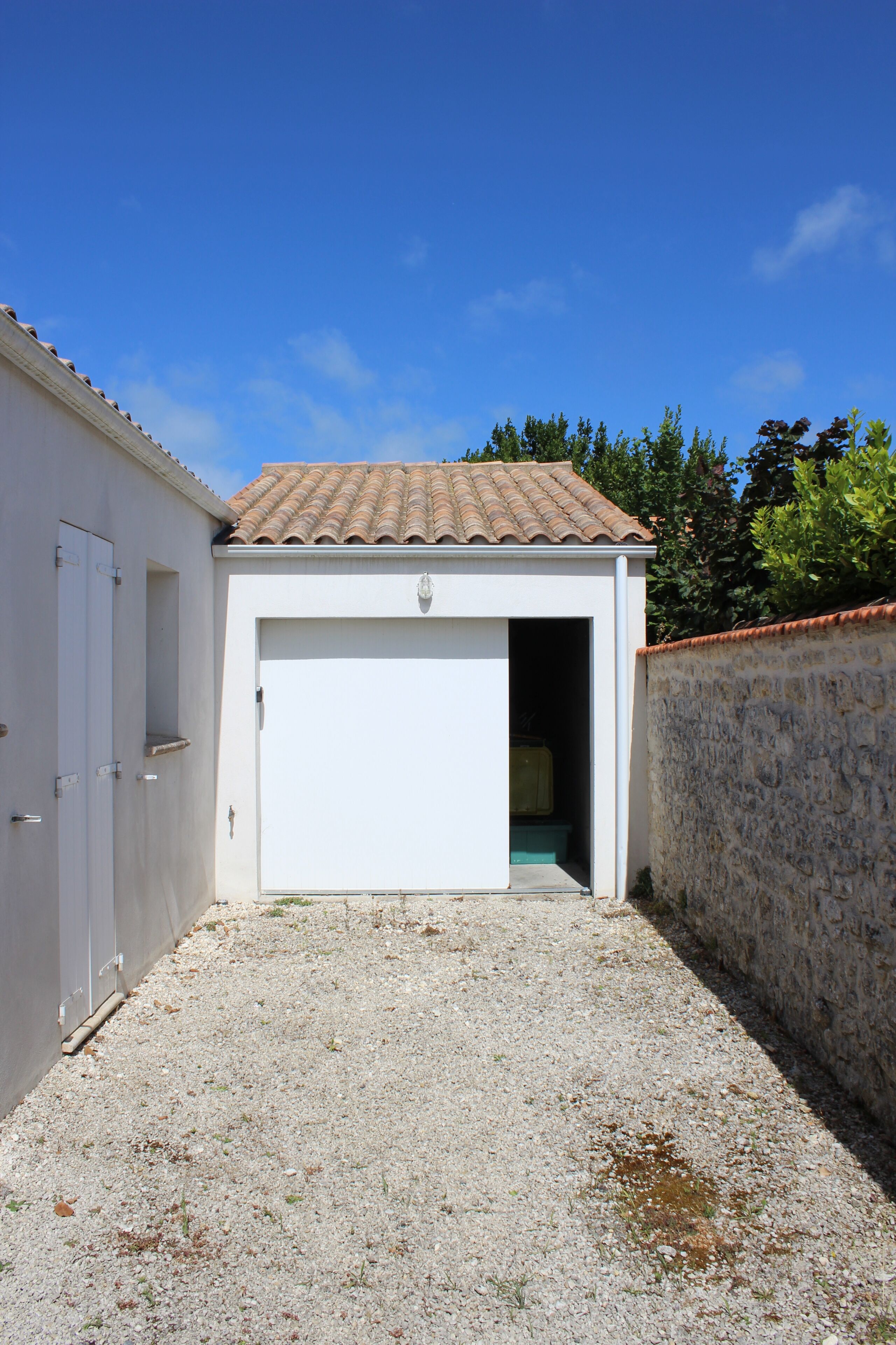 A building with a white exterior, a tiled roof, and a gravel driveway.